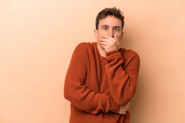 Beyazlı genç adam bej arka planda izole edilmiş korkmuş ve korkmuş..