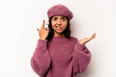 Beyaz arka planda izole edilmiş genç İspanyol kadın elinde bir ürün tutuyor ve.