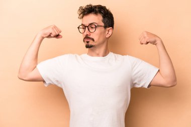 Beyaz tenli genç adam bej arka planda izole edilmiş. Güçlü bir hareket sergiliyor. Kadın gücünün sembolü.