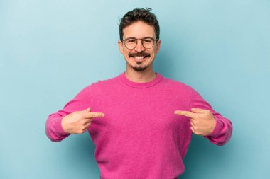 Kafkasyalı genç adam mavi arka planda izole edildi. Parmakları aşağıda, olumlu bir his var..