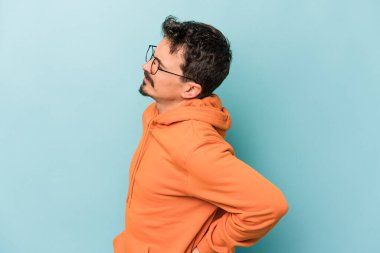 Mavi arka planda izole edilmiş beyaz bir adam sırt ağrısı çekiyor..