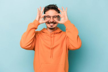 Mavi arka planda izole edilmiş genç beyaz adam gözlerinde sorun olmadığını gösteriyor.