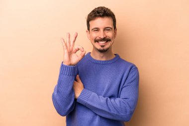 Beyazlı genç bir adam bej arka planda izole edilmiş bir şekilde göz açıp kapayıncaya kadar elinde iyi bir el hareketi tutuyor..