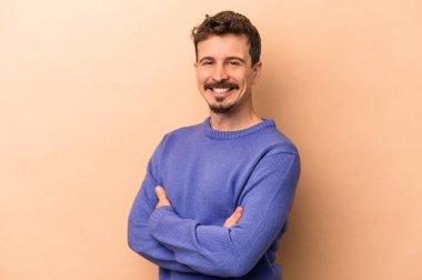 Beyaz tenli genç adam bej arka planda izole edilmiş mutlu, güler yüzlü ve neşeli.