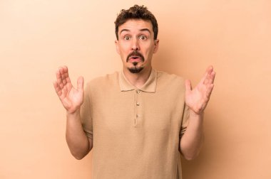 Beyazlı genç bir adam bej arka planda izole edilmiş. Bir fikri, ilham verici bir fikri var..