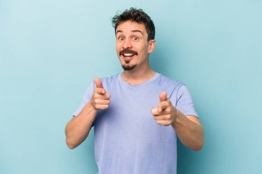 Mavi arka planda izole edilmiş genç beyaz adam öne bakan neşeli gülümsemeler.