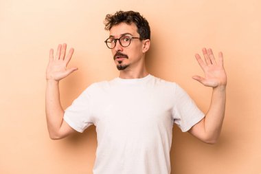 Beyazlı genç bir adam bej arka planda izole edildi. Yakın bir tehlike nedeniyle şoka girdi.