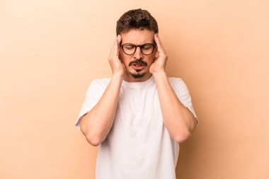 Kafkasyalı genç bir adam bej arka planda izole edilmiş, başı ağrıyor, yüzüne dokunuyor..