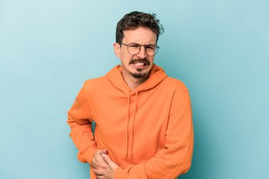 Mavi arka planda karaciğer ağrısı çeken, karnı ağrıyan genç beyaz bir adam..