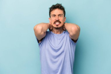 Mavi arka planda izole edilmiş genç beyaz adam öfkeyle bağırıyor..