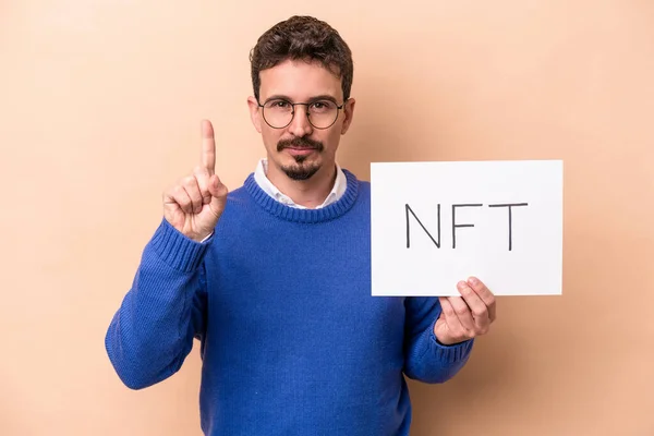 Jovem Caucasiano Segurando Cartaz Nft Isolado Fundo Bege Mostrando Número — Fotografia de Stock