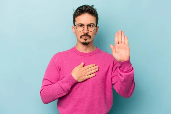 Young Caucasian Man Isolated Blue Background Taking Oath Putting Hand — Stock Photo, Image