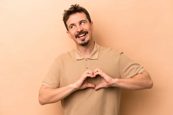 Jonge Blanke Man Geïsoleerd Beige Achtergrond Glimlachen Tonen Een Hartvorm — Stockfoto