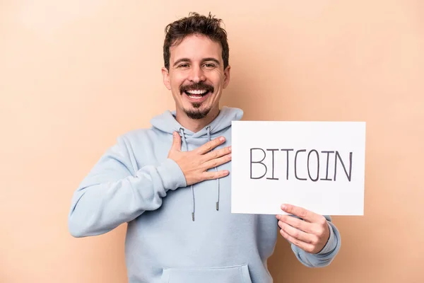 Young Caucasian Man Holding Bitcoin Placard Isolated Beige Background Laughs — Stock Photo, Image