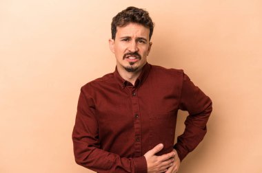 Beyazlı genç bir adam bej arka planda izole edilmiş karaciğer ağrısı, karın ağrısı var..