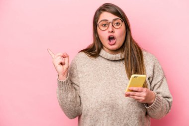 Pembe arka planda izole edilmiş cep telefonu tutan beyaz, şişman bir kadın var.