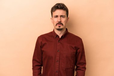 Beyazlı genç bir adam bej arka planda izole edilmiş üzgün, ciddi yüzlü, mutsuz ve hoşnutsuz..