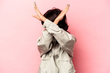 Pembe arka planda izole edilmiş genç İspanyol kadın iki kolu çapraz tutuyor, inkar kavramı.