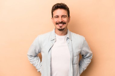Beyaz tenli genç adam bej arka planda izole edilmiş mutlu, güler yüzlü ve neşeli.
