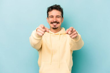 Mavi arka planda izole edilmiş genç beyaz adam öne bakan neşeli gülümsemeler.