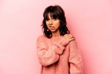 Pembe arka planda izole edilmiş genç İspanyol kadın omuz ağrısı çekiyor..