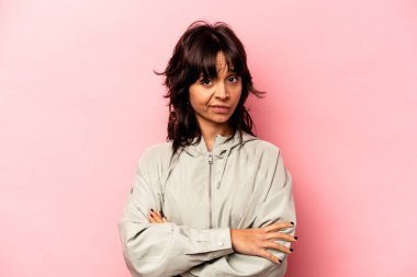 Pembe arka planda izole edilmiş genç İspanyol kadın şüpheli, belirsiz, seni muayene ediyor..