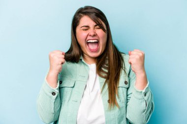 Beyaz, şişman bir kadın mavi arka planda izole edilmiş tasasız ve heyecanlı bir şekilde tezahürat yapıyor. Zafer konsepti.