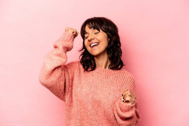 Pembe arka planda izole edilmiş genç İspanyol kadın zaferi, tutkuyu ve coşkuyu kutluyor, mutlu bir ifade..