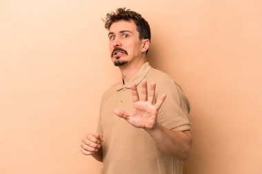 Beyazlı genç bir adam bej arka planda izole edildi. Yakın bir tehlike nedeniyle şoka girdi.