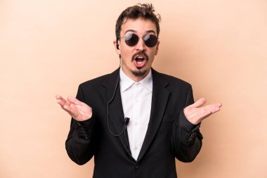 Kafkasyalı genç koruma bej arka planda izole edilmiş, şaşırmış ve şok olmuş..