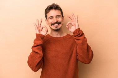 Beyaz tenli genç adam bej arka planda izole edildi. Neşeli ve kendinden emin..