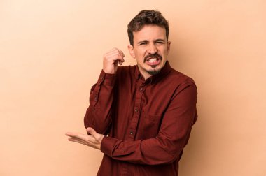 Beyazlı genç adam bej arka planda izole edilmiş dirsek masajı yapıyor, kötü bir hareketin ardından acı çekiyor..