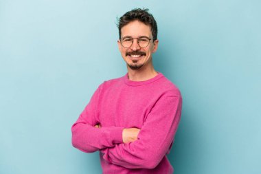 Mavi arka planda izole edilmiş genç beyaz adam mutlu, güler yüzlü ve neşeli.