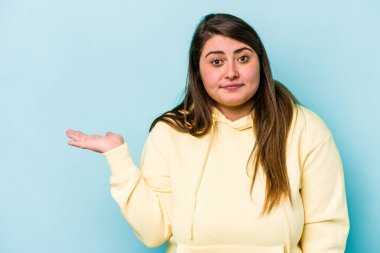 Mavi arka planda izole edilmiş beyaz, genç bir kadın bir avuç içinde fotokopi alanı ve belinde başka bir el tutuyor..