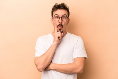 Beyazlı genç bir adam bej arka planda izole edilmiş. Harika bir fikri var, yaratıcılık kavramı..