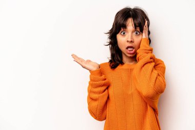 Young hispanic woman isolated on white background impressed holding copy space on palm.