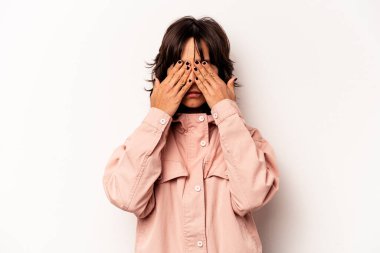 Beyaz arka planda izole edilmiş genç İspanyol kadın elleriyle gözlerini kapatmaktan korkuyor..
