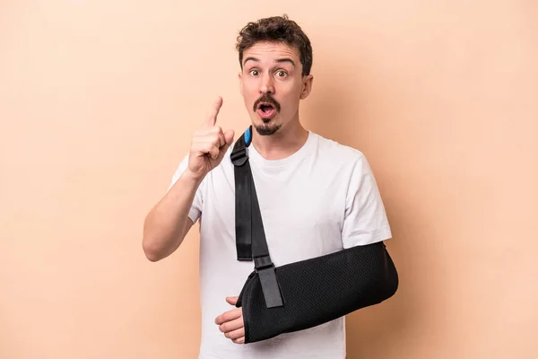 stock image Young caucasian man with broken arm isolated on beige background having an idea, inspiration concept.