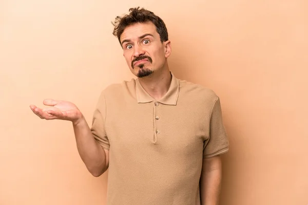 Young Caucasian Man Isolated Beige Background Doubting Shrugging Shoulders Questioning — Stock Photo, Image