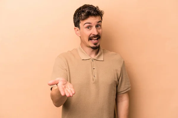 Young Caucasian Man Isolated Beige Background Stretching Hand Camera Greeting — Stock Photo, Image