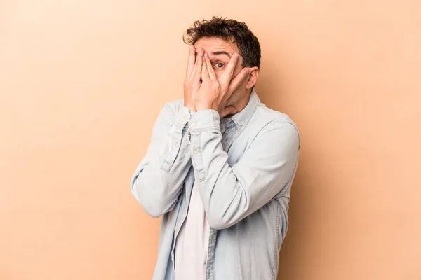 Joven Hombre Caucásico Aislado Sobre Fondo Beige Parpadear Través Los — Foto de Stock