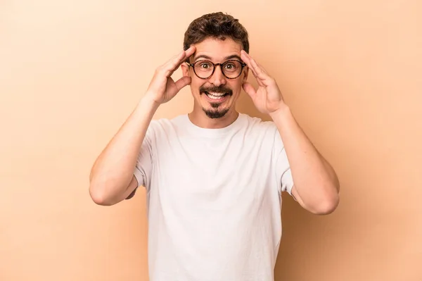 Mladý Běloch Izolovaný Béžovém Pozadí Obdrží Příjemné Překvapení Vzrušení Zvedání — Stock fotografie