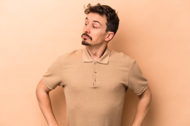 Beyazlı genç bir adam bej arka planda izole edilmiş amaçlarına ve amaçlarına ulaşmayı hayal ediyor.