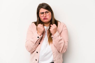 Beyaz arka planda izole edilmiş beyaz tenli genç beyaz kadın yumruğunu kameraya gösteriyor, agresif yüz ifadesi..