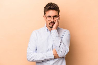 Bej arka planda izole edilmiş beyaz bir genç. Sıkılmış, yorgun ve dinlenmeye ihtiyacı var..