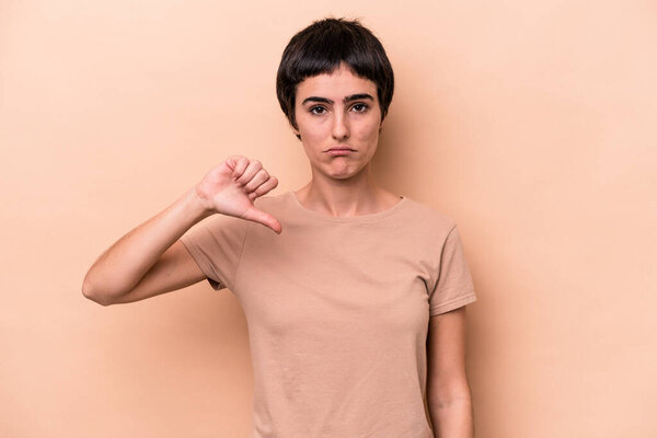 Young caucasian woman isolated on beige background showing a dislike gesture, thumbs down. Disagreement concept.