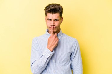 Kafkasyalı genç adam sarı arka planda izole edilmiş düşünüyor ve yukarı bakıyor, yansıtıyor, düşünüyor, hayal kuruyor..