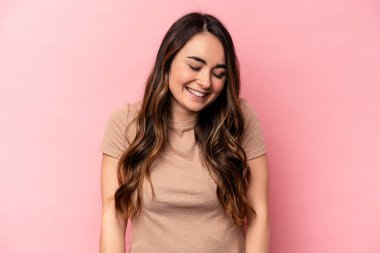 Pembe arka planda izole edilmiş genç beyaz kadın gülüyor ve gözlerini kapıyor, rahatlamış ve mutlu hissediyor..