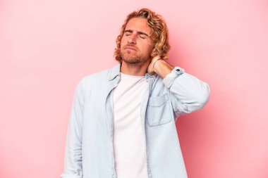 Genç beyaz adam pembe arka planda izole edilmiş dirsek masajı yapıyor, kötü bir hareketin ardından acı çekiyor..