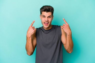 Mavi arka planda izole edilmiş genç beyaz adam işaret parmağıyla bir hayal kırıklığı jesti gösteriyor..